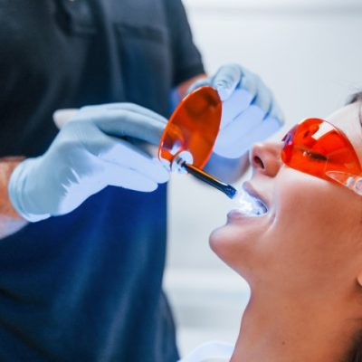 Beautiful woman in red protective glasses have a visit in the dentist clinic. Conception of stomatology.